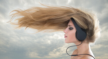 Young woman  listening to music on headphones wind nazvivaet hair 