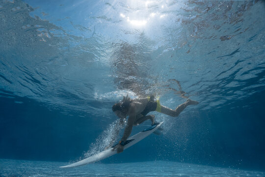 Picture of Surfing a Wave. Under Water Picture. Surfer with surf board dive underwater with fun under big ocean wave
