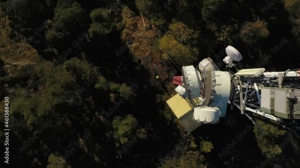 Poster aerial view above a engineer standing on bottom of a telecom tower - rising, drone shot