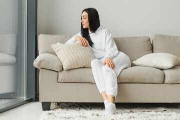 Obraz premium Happy woman relaxing on comfortable soft sofa enjoying stress free weekend at home, calm satisfied girl stretching on couch thinking of pleasant lazy day, dreaming and planning sunday morning
