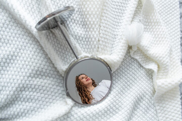 Young woman reflected in the mirror that lies on the bed. Self admiration and acceptance of body...