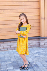 a little girl, in the summer in a city park, smiling happily, resting after school and college lessons, notebooks, folders, textbooks in her hands. Free space for text