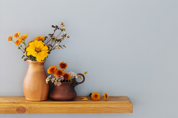 autumn flowers in rustic ceramic vase on background gray wall