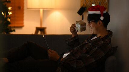 Cheerful asian man wearing Santa hat and having video call with his family on laptop for celebrating holiday together.