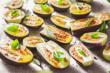 Small raw eggplants prepared for baking on baking sheet