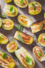 Small raw eggplants prepared for baking on baking sheet