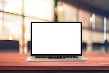 Fototapeta premium Laptop or notebook with blank screen on wood table in blurry background with coffee shop or modern office ,nature orange bokeh and sunlight in morning.vintage tone