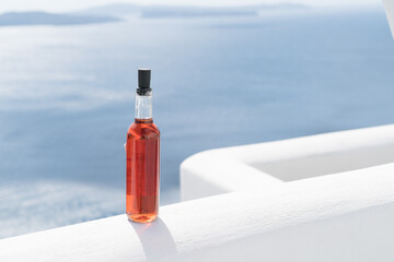 A bottle of red wine on a white wall against the background of the sea in the Greek village of Oia