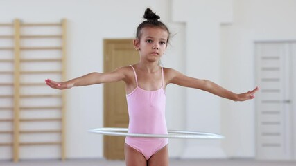 A little acrobatic girl training with a hoop in ballet studio
