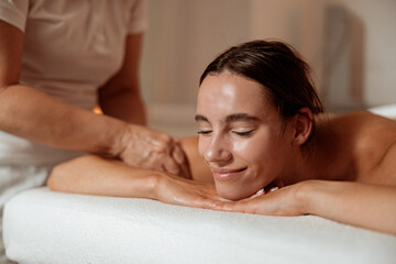 Fototapeta na wymiar Joyful young woman receiving professional massage in spa salon