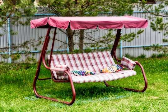Swing bench with a canopy on a green grassy lawn