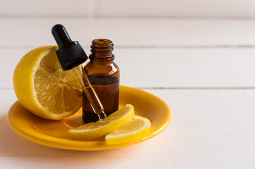 serum with lemon extraty for facial skin care in a glass flaon with a pipette and lemon fruit on a yellow plate.
