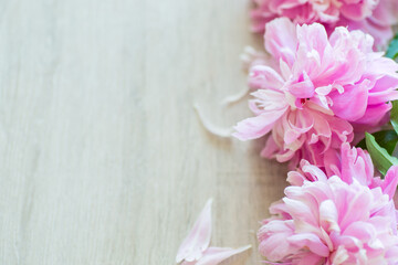 several branches of blooming pink peonies on a wooden table
