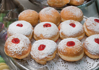 Fresh donuts with jelly at the bakery display for Hanukkah celebration. Selective focus.
