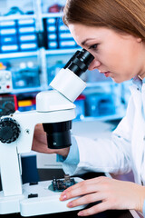 A young woman is testing an electronic module for the production of electric cars. Quality control...