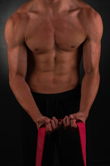 Carved young athlete during workout on black background.  