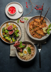 asian dinner with ramen soup, spicy noodle and cucumber salad top view on black background closeup. Selective focus