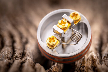 close up shot of single space coil in high end rebuildable dripping atomizer for flavour chaser on rustic natural wood texture background, vaping device