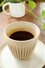 Cup of Hot Coffee with Blurry Potted Marble Queen Plants in Background