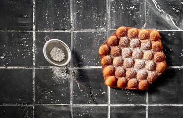 Trendy bubble or egg waffle sprinkled with icing sugar
