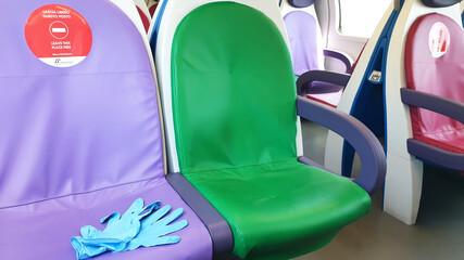 Blue gloves lie on the seat on the train with the inscription: Leave a seat free. An empty train...