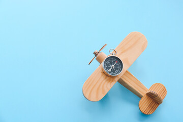 Wooden airplane and compass on color background