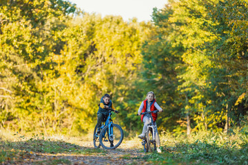 Plakat happy kids ride a bike in the autumn forest
