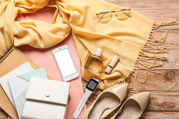 Female clothes, stylish accessories and smartphone on wooden background