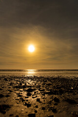 Dinas Dinlle beach with the sun setting reflected in the sea.  Welsh coast beach holiday concept