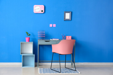 Interior of stylish room with modern workplace and blue wall