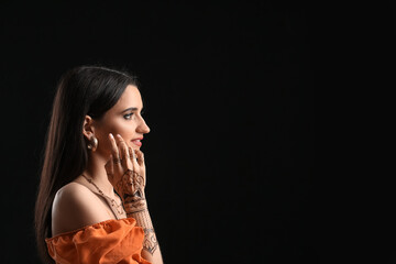 Beautiful Indian woman with henna tattoo on dark background