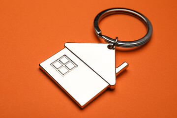 Stylish keychain on orange background, closeup