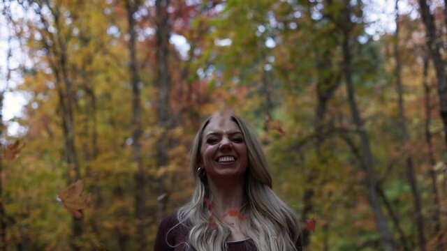 Cheerful Woman Throws Maple Leaf In The Air During Autumn Season In The Park. - low angle