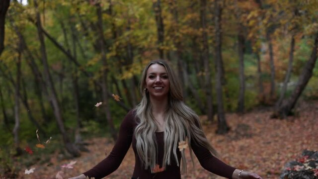 Happy Pretty Girl Throws Handfull Of Autumn Leaves In The Park. - medium shot