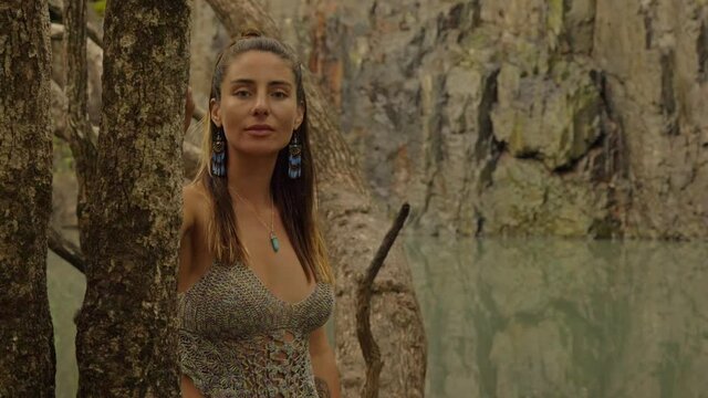Pretty Young Woman Feeling Trunk Of Tree Then Turns Head And Look At Rugged Cliff - Cedar Creek Falls In QLD, Australia. - medium shot