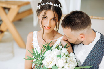 Handsome groom kisses the bride on the shoulder. Portrait of the newlyweds.