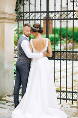 Sensual couple hugging in front of a wrought iron gate.