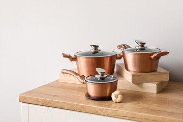 Set of copper cooking pots with garlic on counter near light wall