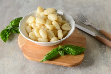 Bowl with tasty gnocchi on grunge background