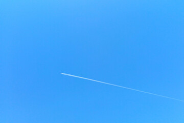 Out of focus, a plane flies against the blue sky.