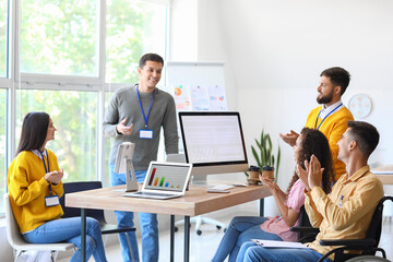 Young business people clapping during meeting in office