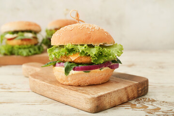 Wooden board with tasty vegetarian burger on table