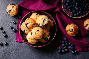 Composition with tasty blueberry muffins and berries on dark background