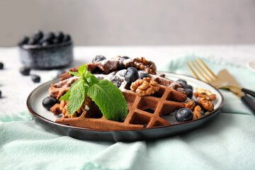 Plate of delicious Chocolate Belgian Waffles with blueberry and walnut on table