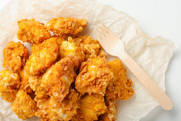Parchment with crunchy popcorn chicken on white background