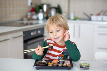 Cute blond child Eat Sushi Rolls At Home. Happy boy ready for eating sushi © Tomsickova