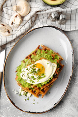 Tasty Belgian waffles with vegetables in plate on light background