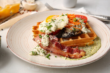Delicious Belgian waffles with egg, bacon and vegetables in plate on light background, closeup