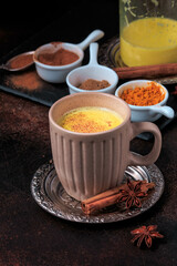 Easy Healthy Golden Milk, Turmeric Latte over dark background. Spices for ayurvedic treatment. Alternative medicine concept.