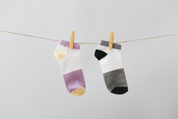 Two different socks hanging on rope against grey background